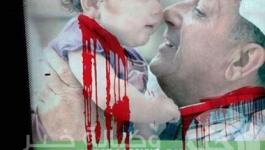 رسم خطوط بلون الدم على لافتة تحمل صورة اب عربي وطفلة وسط تل ابيب