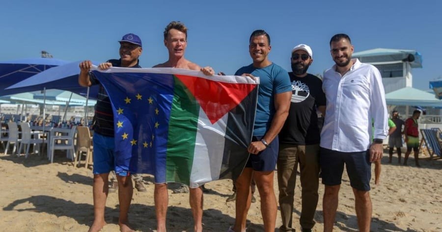 ممثل الاتحاد الأوروبي يرفع العلم الفلسطيني أثناء ممارسته رياضة السباحة في بحر غزة