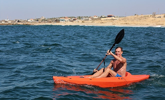 ممثل الاتحاد الأوروبي يرفع العلم الفلسطيني أثناء ممارسته رياضة السباحة في بحر غزة