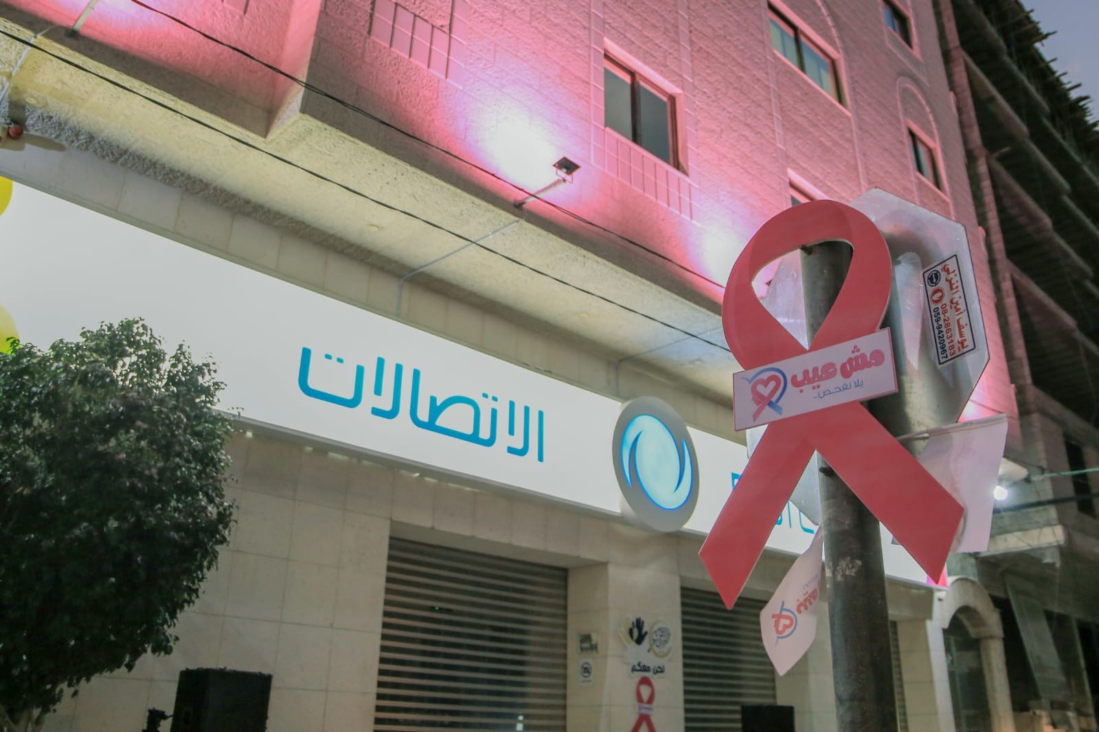 إضاءة مبني الاتصالات الفلسطينية باللون الوردي ضمن حملة "مش عيب يلا نفحص"